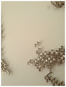 DETAIL – 2013 Metal star charms on stainless steel nails on white lacquered panel 